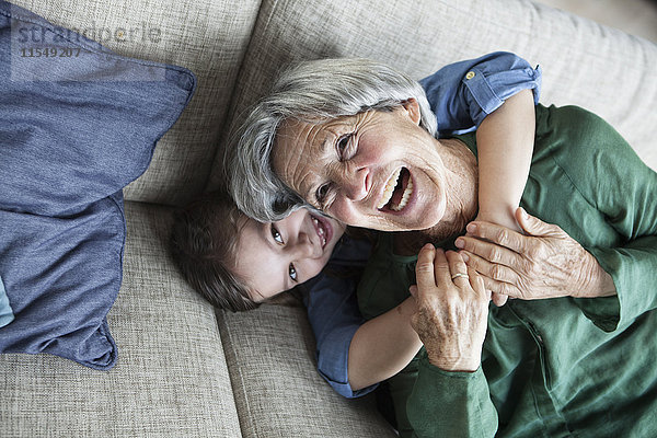 Porträt der lachenden Großmutter und ihrer Enkelin auf der Couch