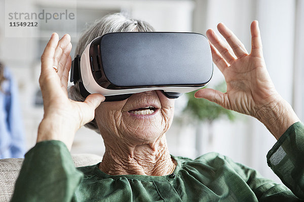 Seniorin mit Virtual Reality Brille zu Hause