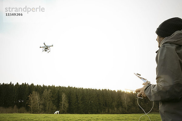 Mann auf einer Wiese fliegende Drohne