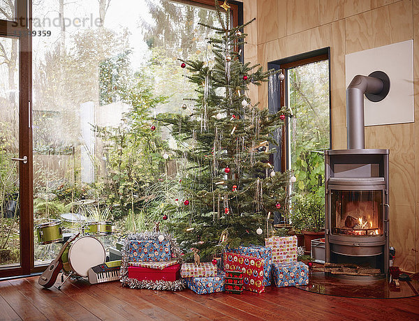 Weihnachtsgeschenke unter dem Weihnachtsbaum neben dem gemütlichen Kamin