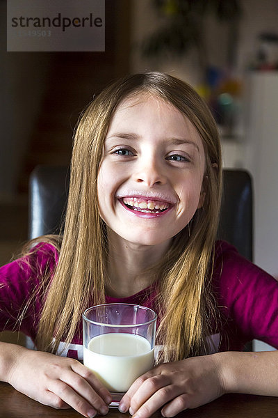 Porträt eines glücklichen Mädchens mit einem Glas Milch