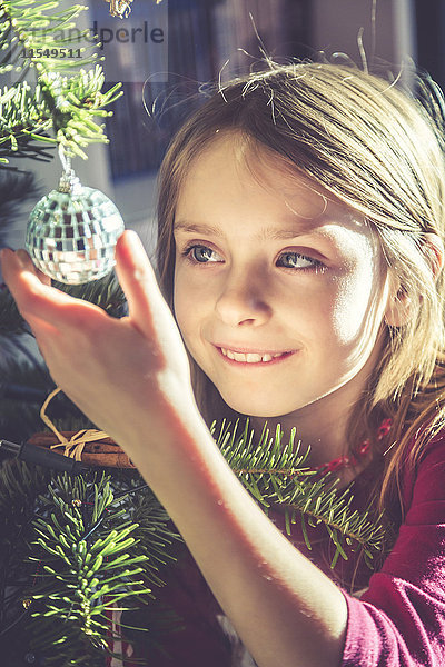 Porträt des lächelnden Mädchens  das den Weihnachtsbaum schmückt