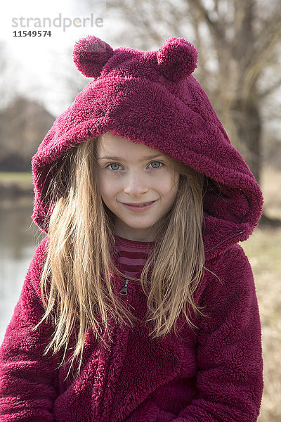 Porträt eines lächelnden Mädchens in Plüsch-Kapuzenjacke mit Ohren