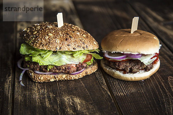 Vegetarischer Burger mit Rübenpastete  Avocadocreme  Salat und Zwiebeln neben einem Hamburger mit Fleischklößchen rechts