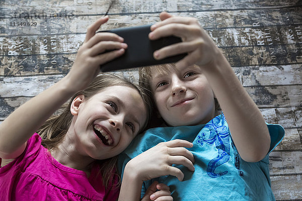Porträt eines Bruders und einer kleinen Schwester  die einen Selfie mit einem Smartphone sprechen.