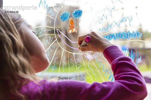 Mädchen malt Sonne auf Fensterscheibe