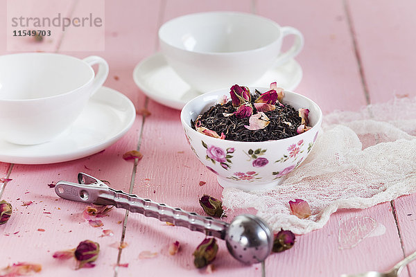 Schale schwarzer Tee mit getrockneten Rosenblüten