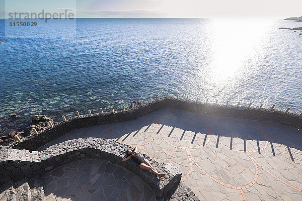 Spanien  Teneriffa  Frau beim Sonnenbaden an der Wand am Meer