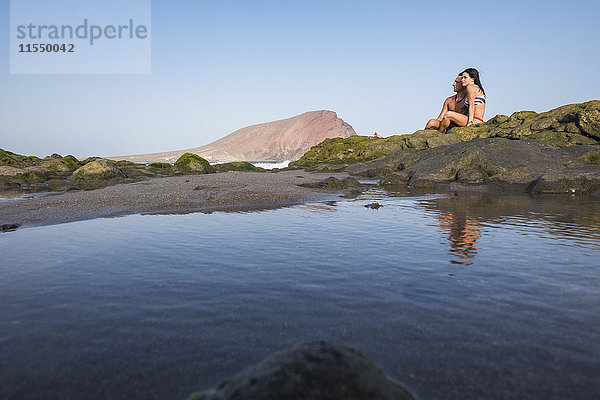 Entspanntes junges Paar auf Felsen am Meer sitzend