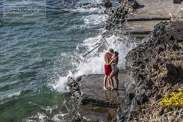 Spanien  Teneriffa  junges verliebtes Paar küsst auf einem Felsvorsprung