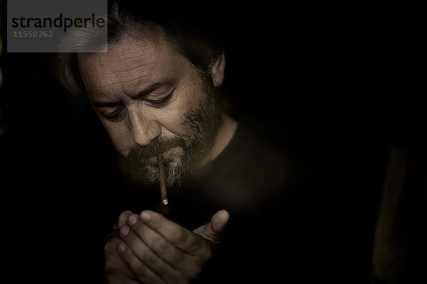 Porträt eines Mannes beim Anzünden eines Zigarillos