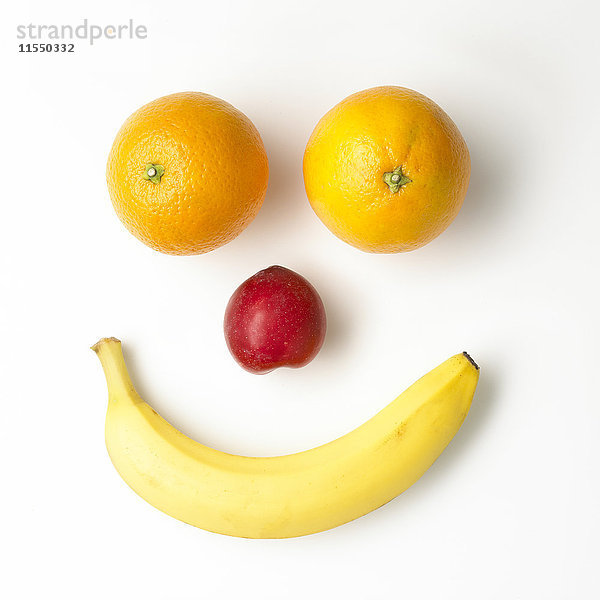 Smiley-Gesicht aus Früchten auf weißem Grund