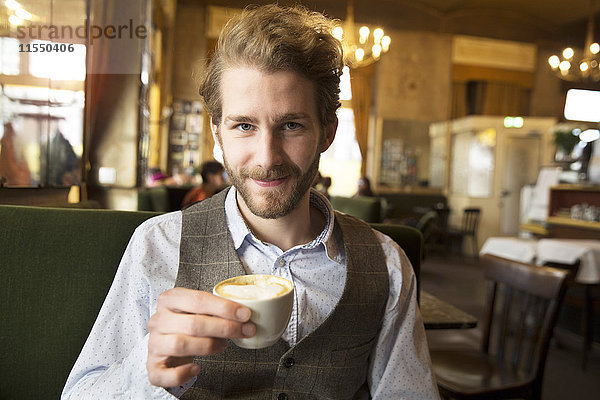 Porträt eines lächelnden jungen Mannes in einem Café
