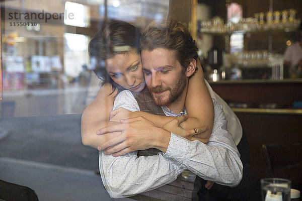 Junges Paar  das sich in einem Cafe umarmt.