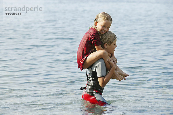 Spanien  Mallorca  Junge mit kleiner Schwester auf den Schultern im Meer