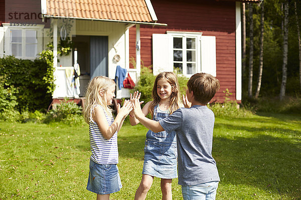 Schweden  drei Kinder spielen auf einer Wiese vor dem Ferienhaus