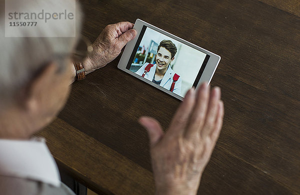 Senior Mann mit Mini-Tablette zum Skypen mit seinem Enkel