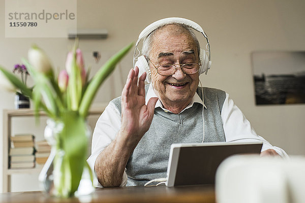 Senior Mann mit Mini-Tablett und Kopfhörer für das Skyping zu Hause