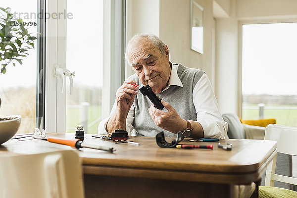 Senior Mann repariert Spielzeugeisenbahn zu Hause