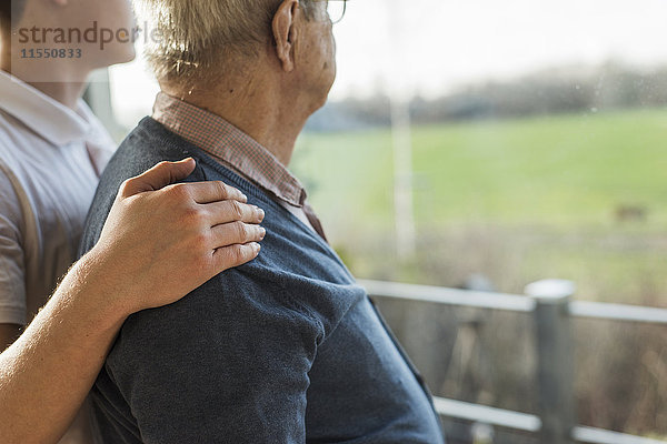 Die Hand eines jungen Mannes auf der Schulter eines älteren Mannes.