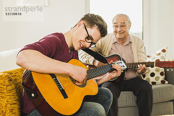 Großvater und Enkel spielen zusammen Gitarre