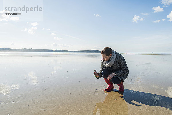 Frankreich  Bretagne  Finistere  Halbinsel Crozon  Frau findet eine Muschel am Strand
