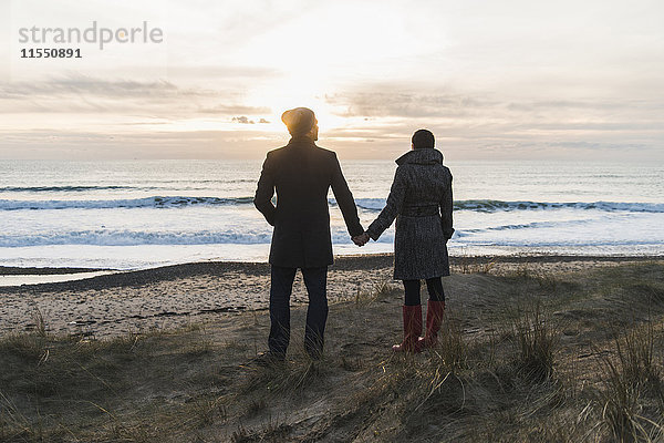 Frankreich  Bretagne  Finistere  Halbinsel Crozon  Paar steht bei Sonnenuntergang an der Küste