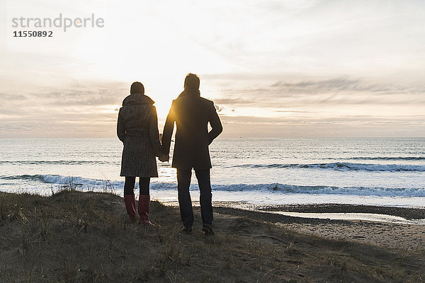 Frankreich  Bretagne  Finistere  Halbinsel Crozon  Paar steht bei Sonnenuntergang an der Küste