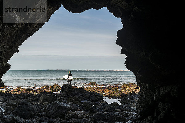 Frankreich  Bretagne  Finistere  Halbinsel Crozon  Mann am Felsenstrand mit Surfbrett