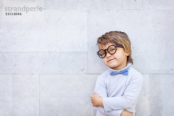 Porträt eines lächelnden kleinen Jungen mit Schleife und übergroßer Brille