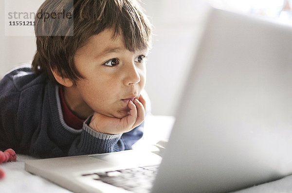 Porträt des kleinen Jungen  der auf den Laptop starrt