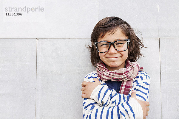 Porträt des grinsenden kleinen Jungen mit Schal und übergroßer Brille