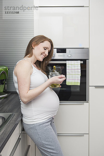 Schwangere in der Küche essen Gurken