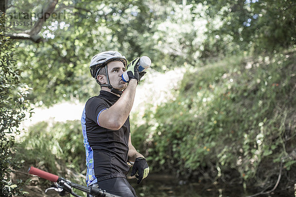 Mann auf dem Mountainbike im Wald Trinkwasser