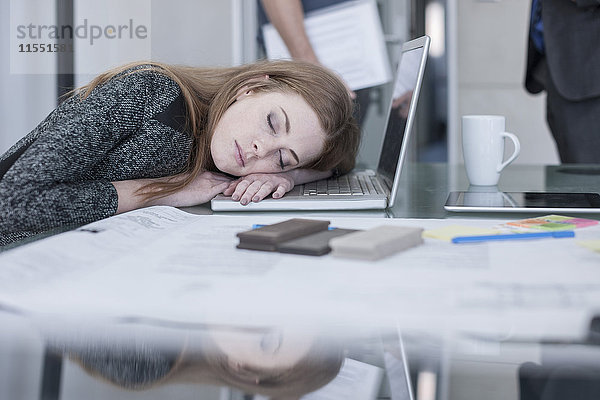 Frau schläft auf dem Tisch im Büro