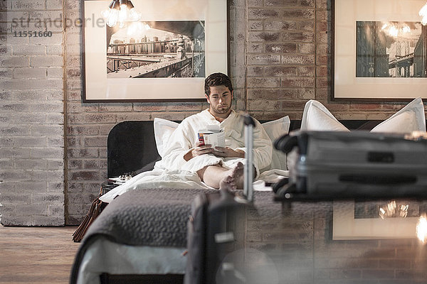 Mann im Hotelbett beim Lesen eines Buches