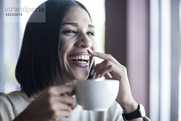 Porträt einer lachenden Frau mit Milchschnurrbart und Kaffeetasse