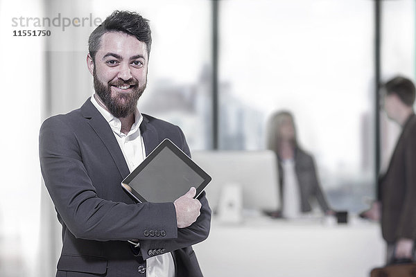 Porträt eines lächelnden Geschäftsmannes mit digitalem Tablett im Büro