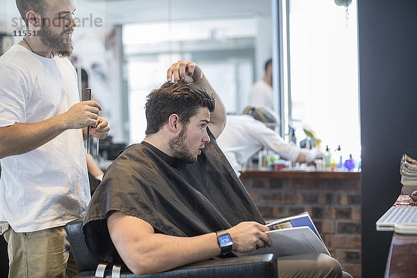 Junger Mann beim Friseur im Gespräch mit dem Friseur