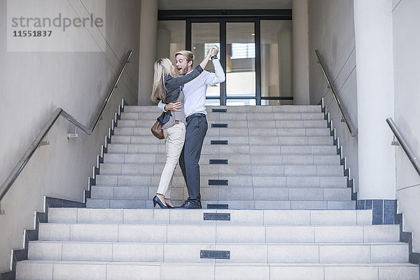 Geschäftsfrau und Mann tanzen auf der Treppe