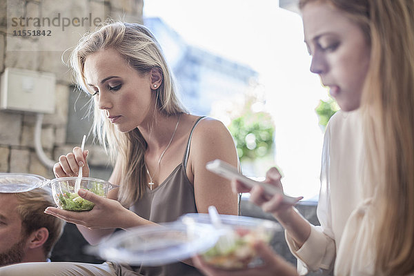 Junge Geschäftsfrauen essen Salat zum Mittagessen