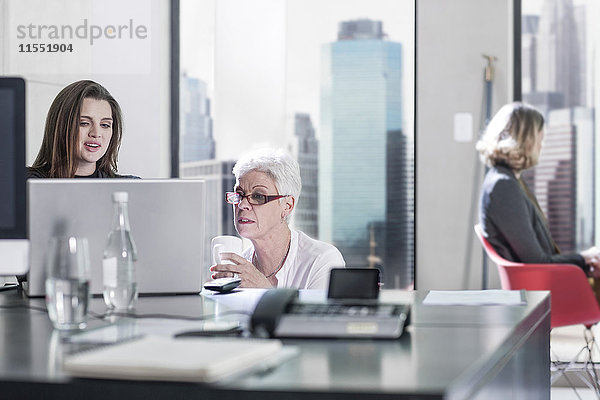 Zwei Frauen im Büro diskutieren am Laptop