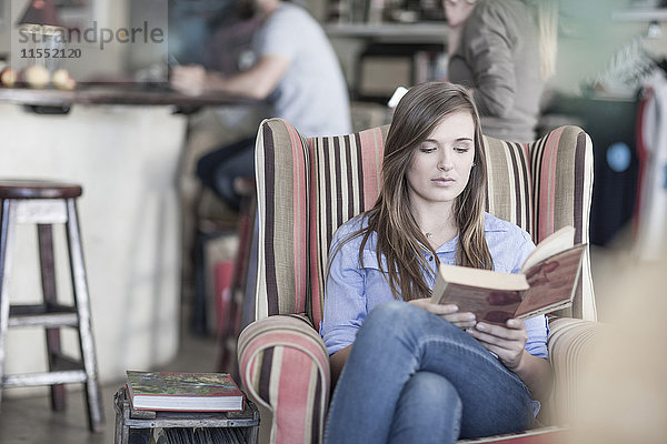 Junge Frau sitzt im Café und liest Buch