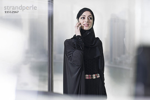 Junge Geschäftsfrau aus dem Nahen Osten im Büro am Telefon
