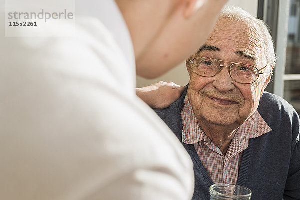 Porträt eines lächelnden älteren Mannes von Angesicht zu Angesicht mit seiner Altenpflegerin