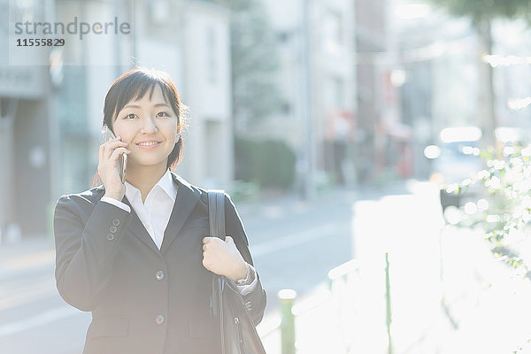 Junge japanische Geschäftsfrau am Telefon in der Innenstadt von Tokio