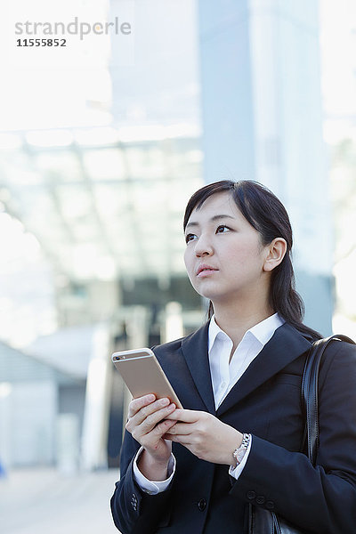 Junge japanische Geschäftsfrau mit Telefon in der Innenstadt von Tokio