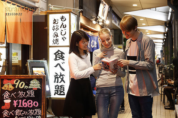 Kaukasisches Touristenpaar auf der Suche nach einem Restaurant in einer traditionellen Einkaufsstraße  Tokio  Japan