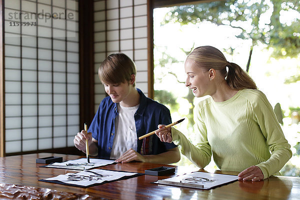 Kaukasisches Paar übt Kalligraphie in einem traditionellen japanischen Haus