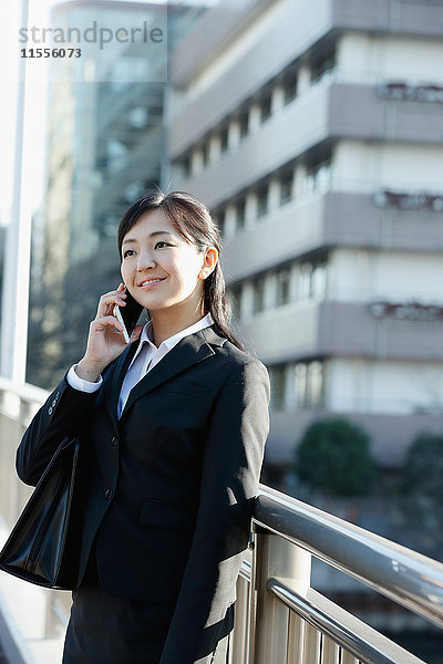 Junge japanische Geschäftsfrau am Telefon in der Innenstadt von Tokio